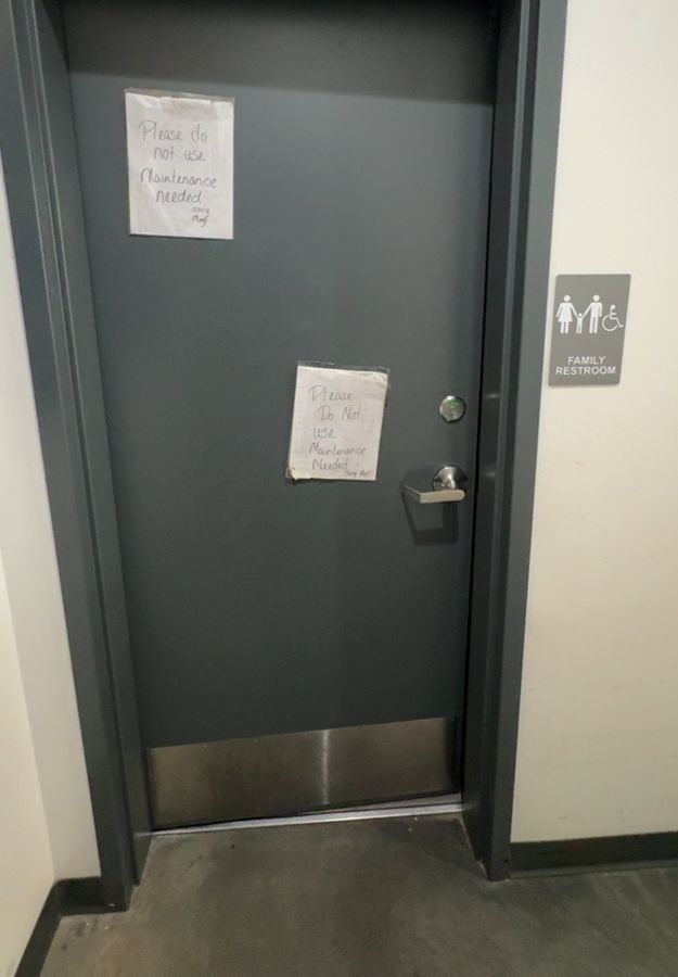 Restroom door taped with maintenance-needed notes before repair, Charlotte NC
