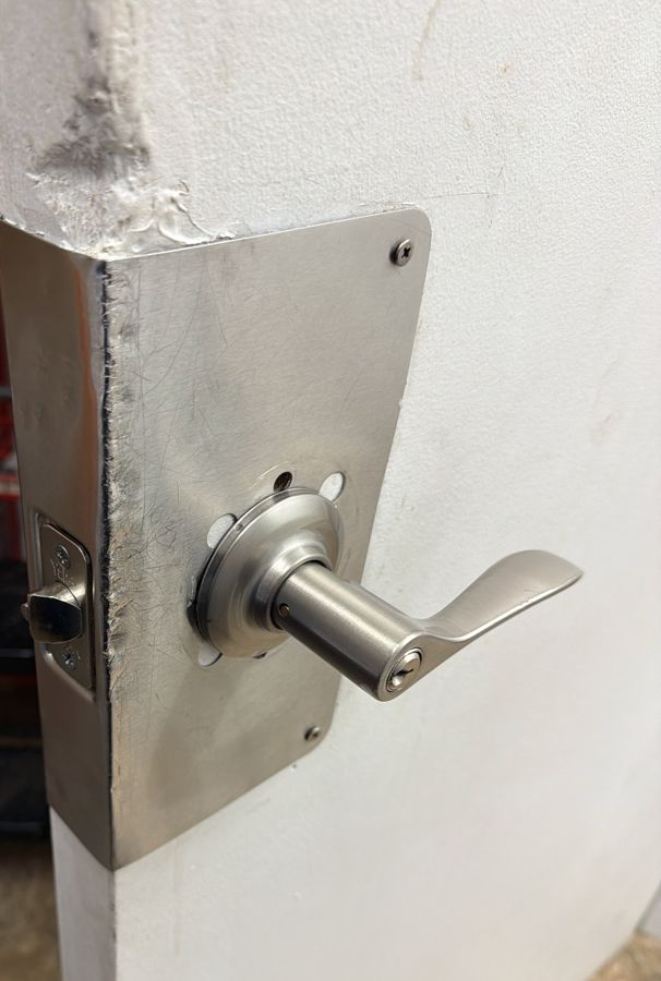 Keyed lever on a back-room door with a scuffed edge guard, before the lock was replaced, Charlotte NC
